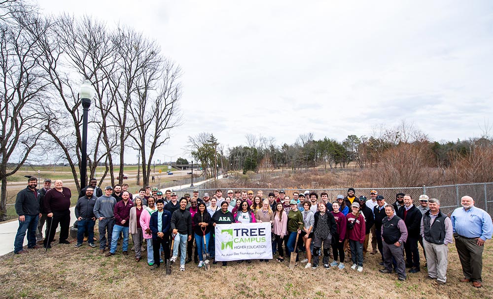 A large crowd of MSU students, faculty and staff with a Tree Campus USA banner at the Arbor Day celebration